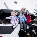 Auto so strešným boxom zaparkované v prírode, pripravené na rodinný výlet.