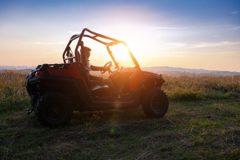 Nákladná štvorkolka a ATV s vozíkom zaparkované vedľa seba na dvore.
